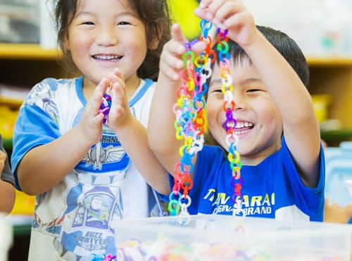 カラフルなチェーンを作って遊ぶ子どもたちが笑顔で楽しんでいる様子
