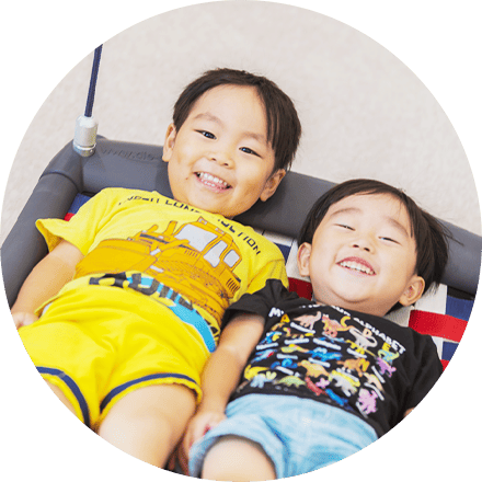 ハンモックで笑顔を見せながら仲良くくつろぐ2人の子どもたち