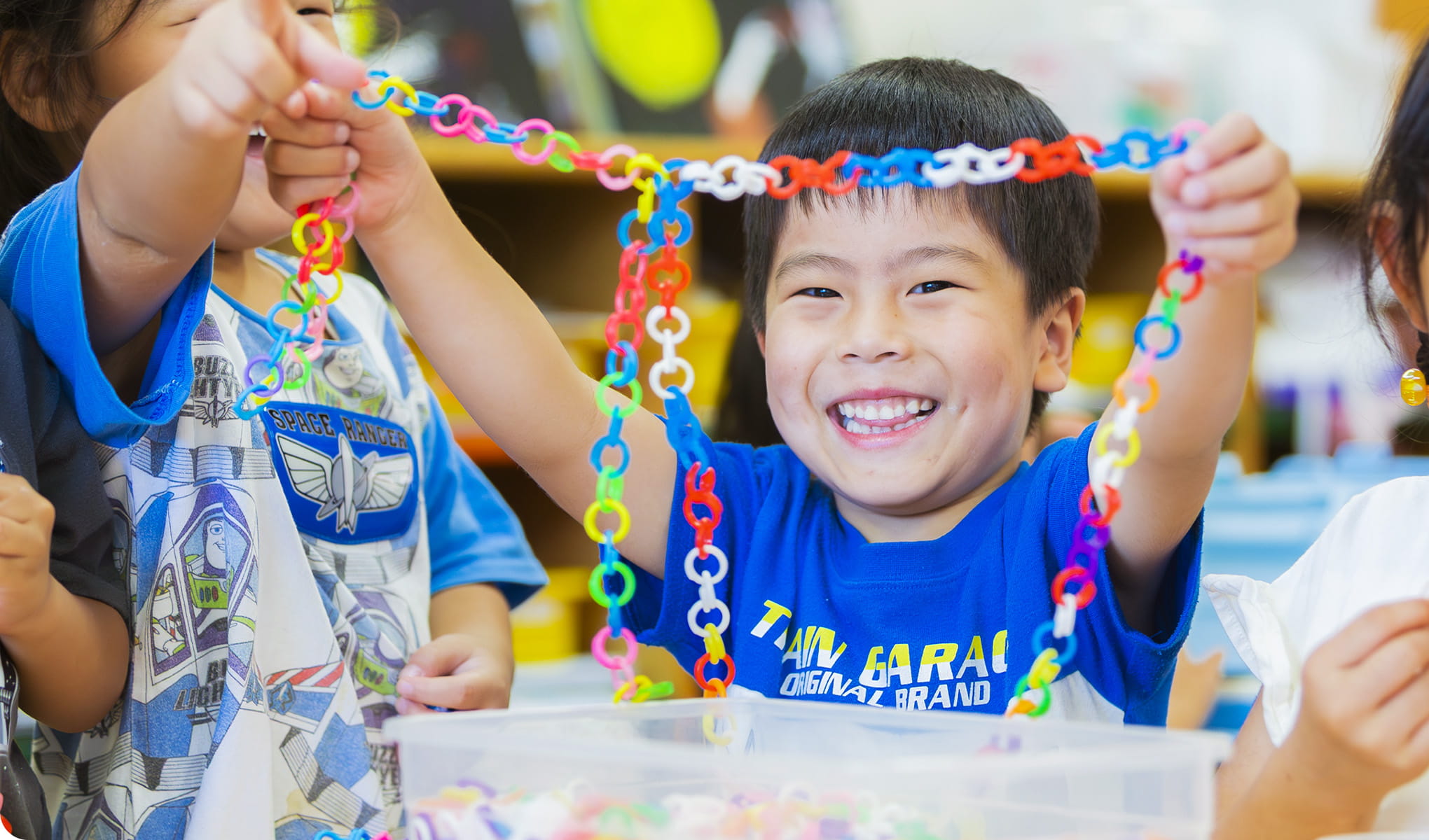男の子がカラフルなチェーン状のおもちゃを手に持ち、笑顔を見せている