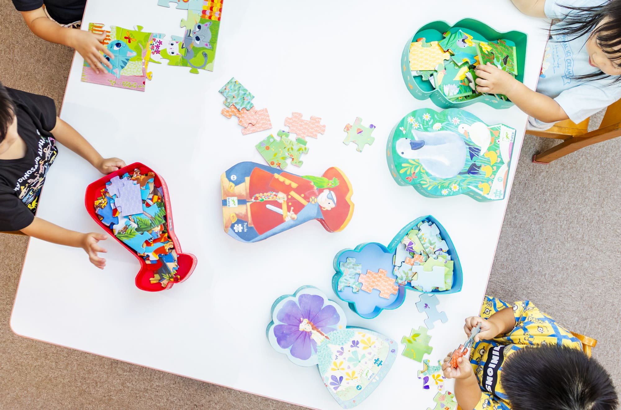 テーブルに広げたパズルに夢中で取り組む子どもたち