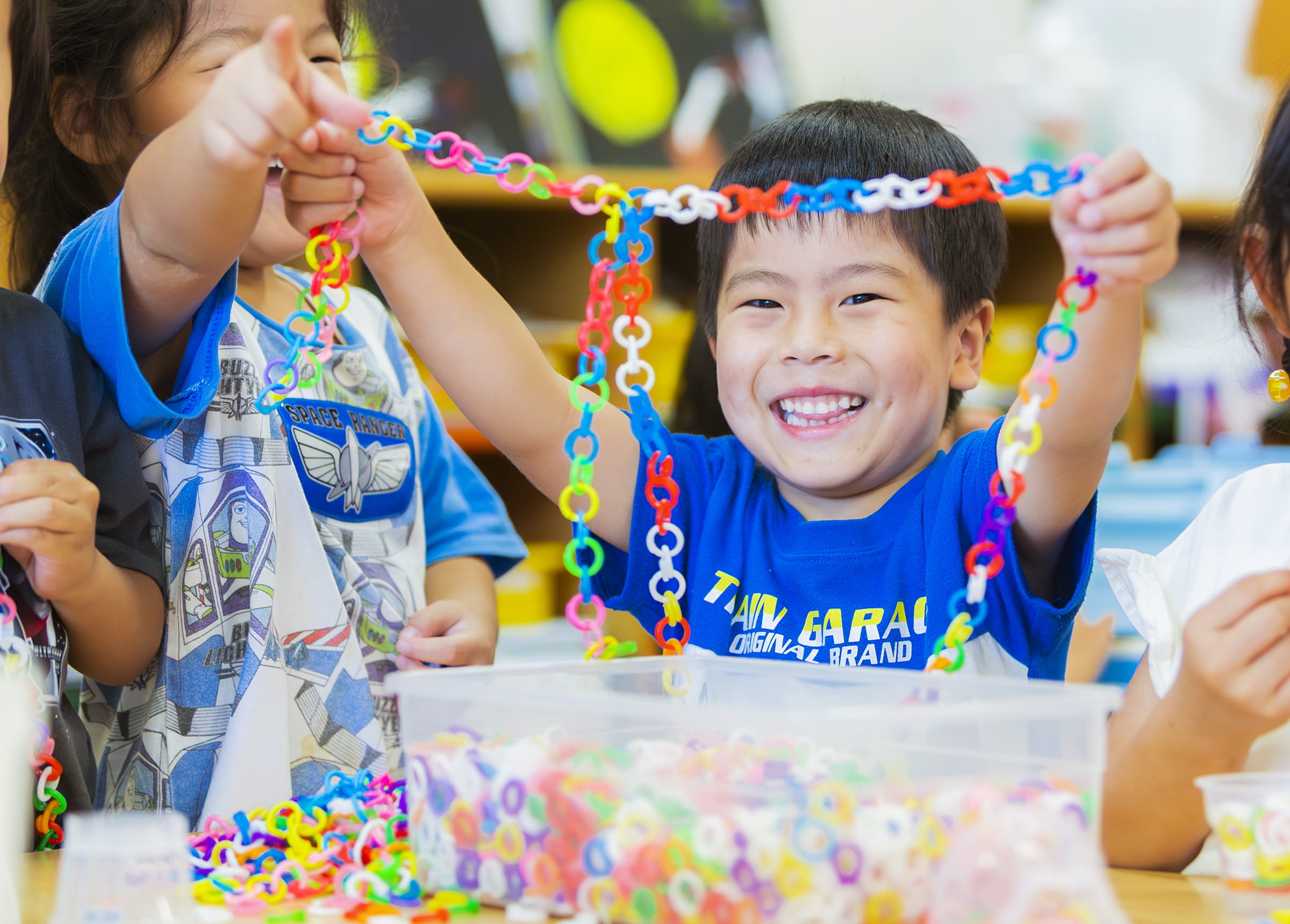 男の子がカラフルなチェーン状のおもちゃを手に持ち、笑顔を見せている