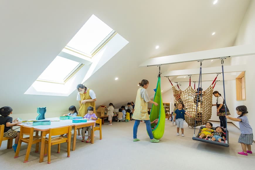室内ブランコやハンモック、テーブル遊びなど多様な活動が行われている空間